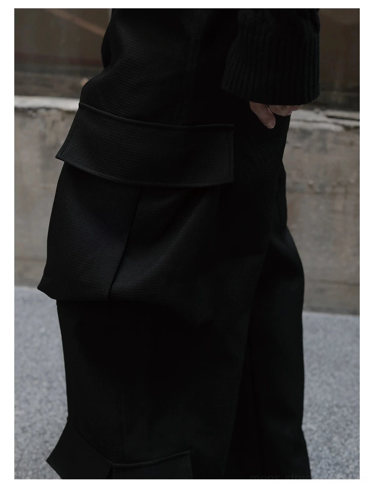 Close-up of layered black cargo pockets with reinforced stitching and matte textured polyester fabric