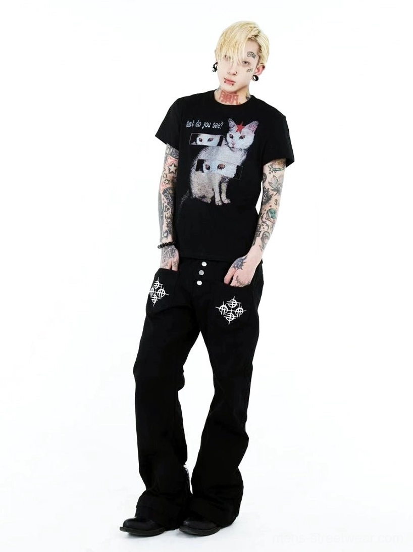 Three-quarter front view of a black cat optical illusion graphic T-shirt with white feline artwork, repeated eye panels, and What do you see slogan styled with black streetwear denim