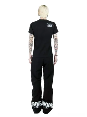 Full back view of black cat graphic streetwear T-shirt showing small cassette-style upper back print and matching slogan with black denim outfit