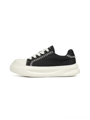 Black chain-trim platform sneakers with white contrast stitching, white toe cap, laces, and thick off-white rubber sole shown from a left front angle