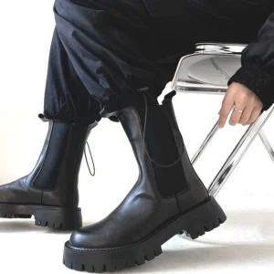 Front three-quarter view of black chunky Chelsea boots worn with cropped cargo pants, showing elastic gores, rounded toes, and ridged platform soles