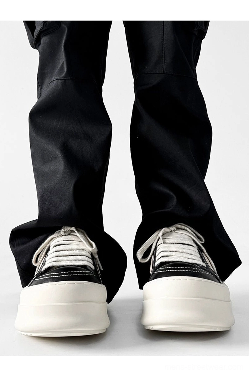 Black chunky platform sneakers with white laces and thick off-white soles worn from the front