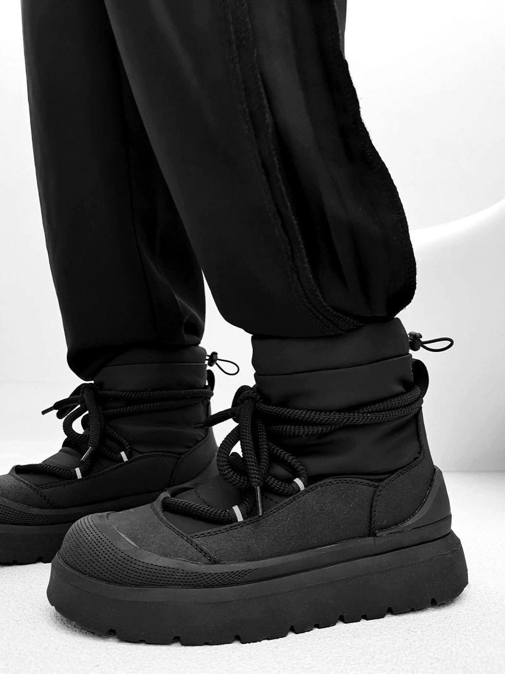 Front angled view of black chunky platform snow boots with textured toe cap and thick rubber platform outsole