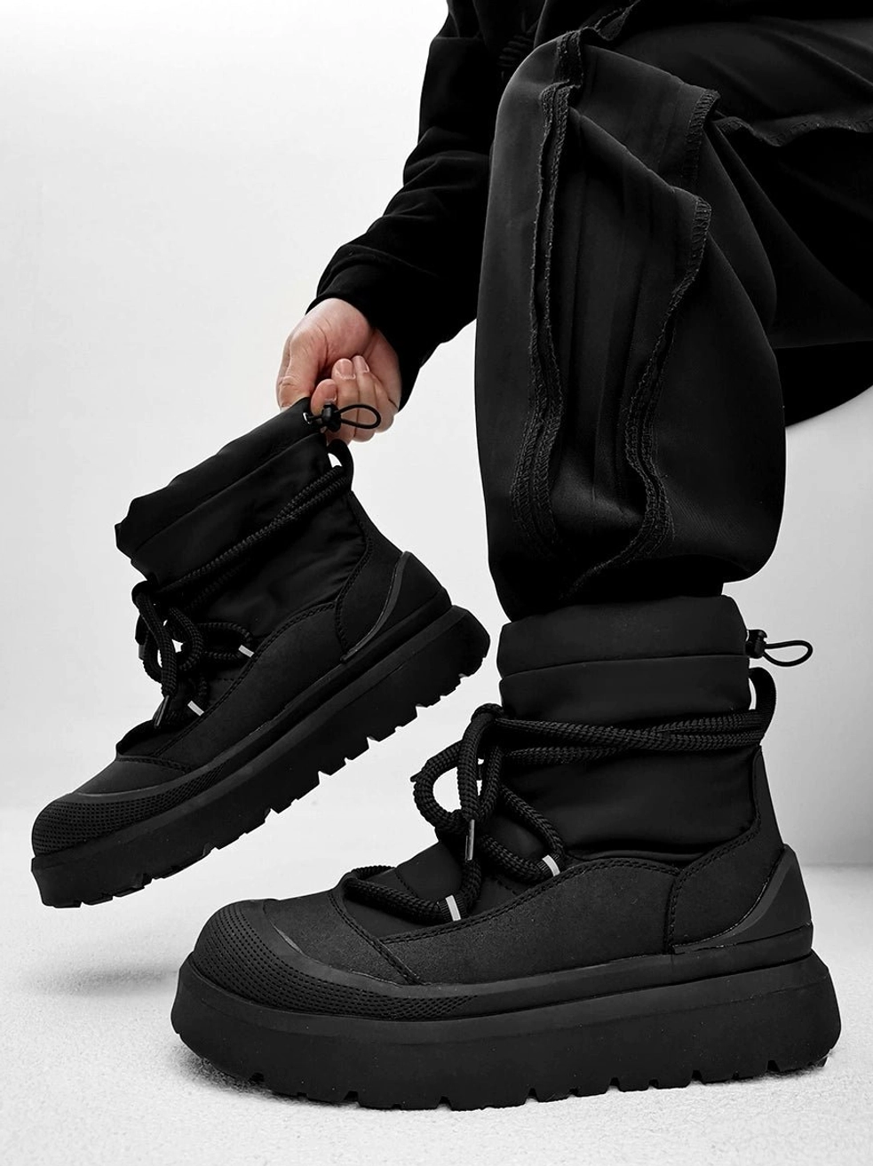 Black chunky platform winter boots worn with black cargo pants in an overhead streetwear outfit view