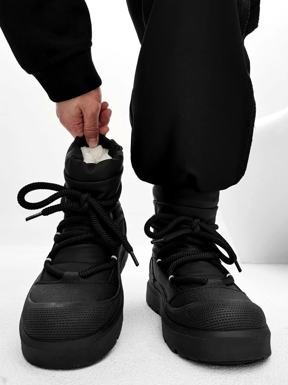 Front view of black chunky platform winter boots with plush faux fur lining round laces and lug rubber sole