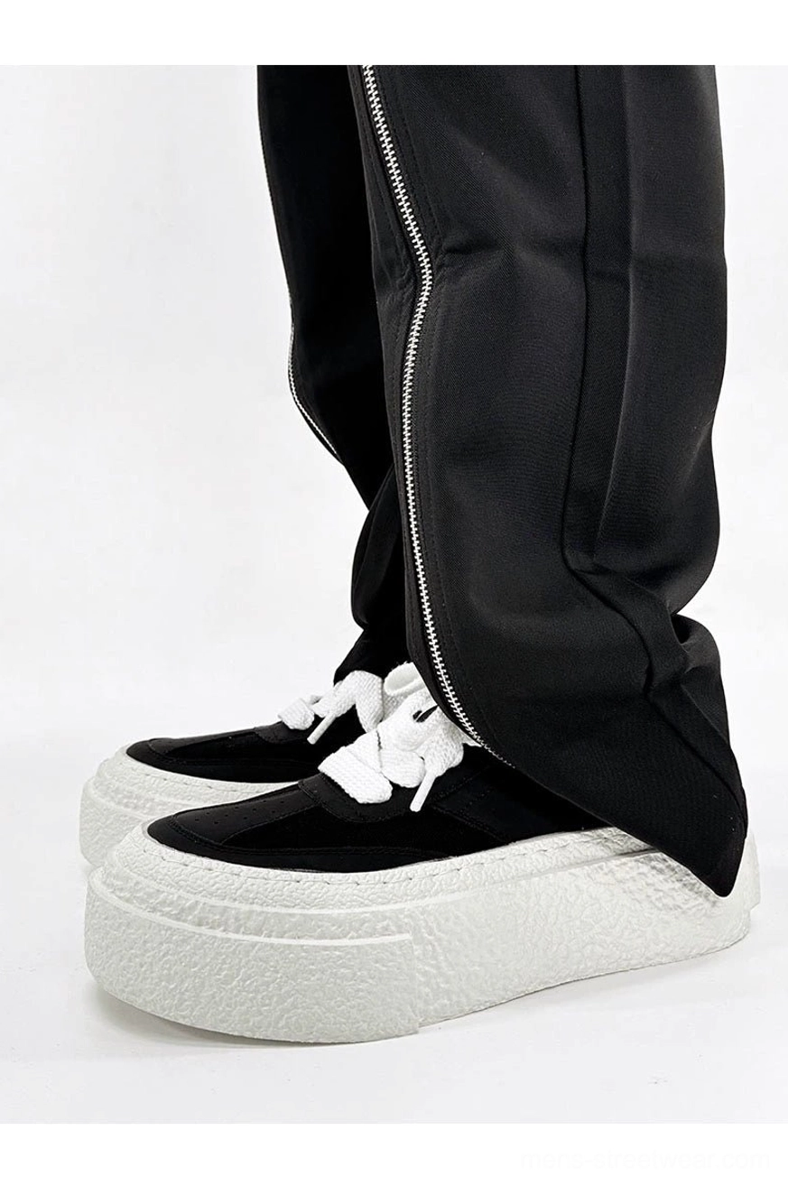 Black chunky streetwear sneakers with bright white thick rubber soles shown from the front side