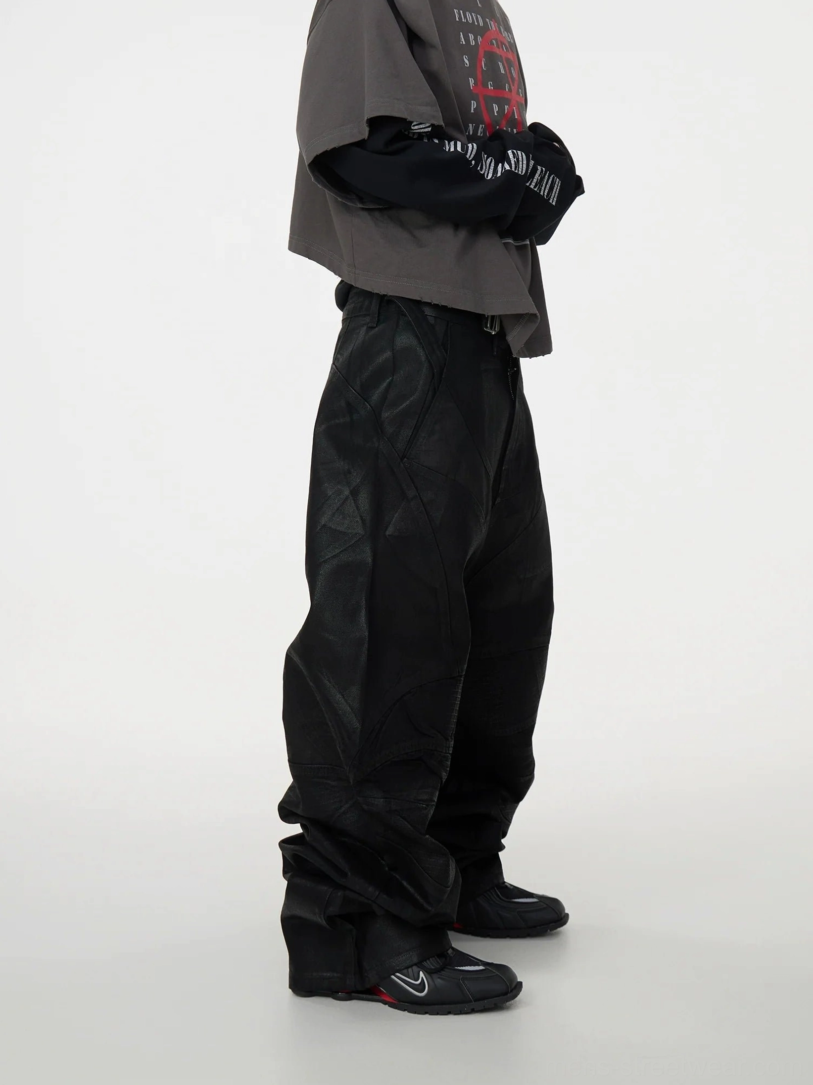 Left side view of black coated patchwork denim jeans with geometric sewn panels, oversized baggy legs, stacked hem, and Japanese-inspired avant-garde streetwear proportions