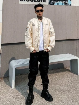 Men's black combat cargo jogger pants in a full front streetwear outfit with side cargo pockets, tapered ankles, combat boots, and a cream flight jacket
