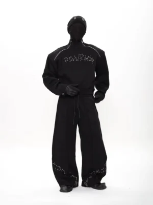 Black oversized tech fleece two-piece streetwear outfit shown from the side front with constellation chest embroidery, zippered raglan shoulders, and loose wide-leg trousers