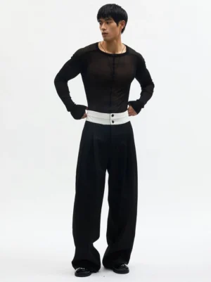 Black contrast ivory waistband high-rise wide-leg pleated trousers worn by male model in white studio front view