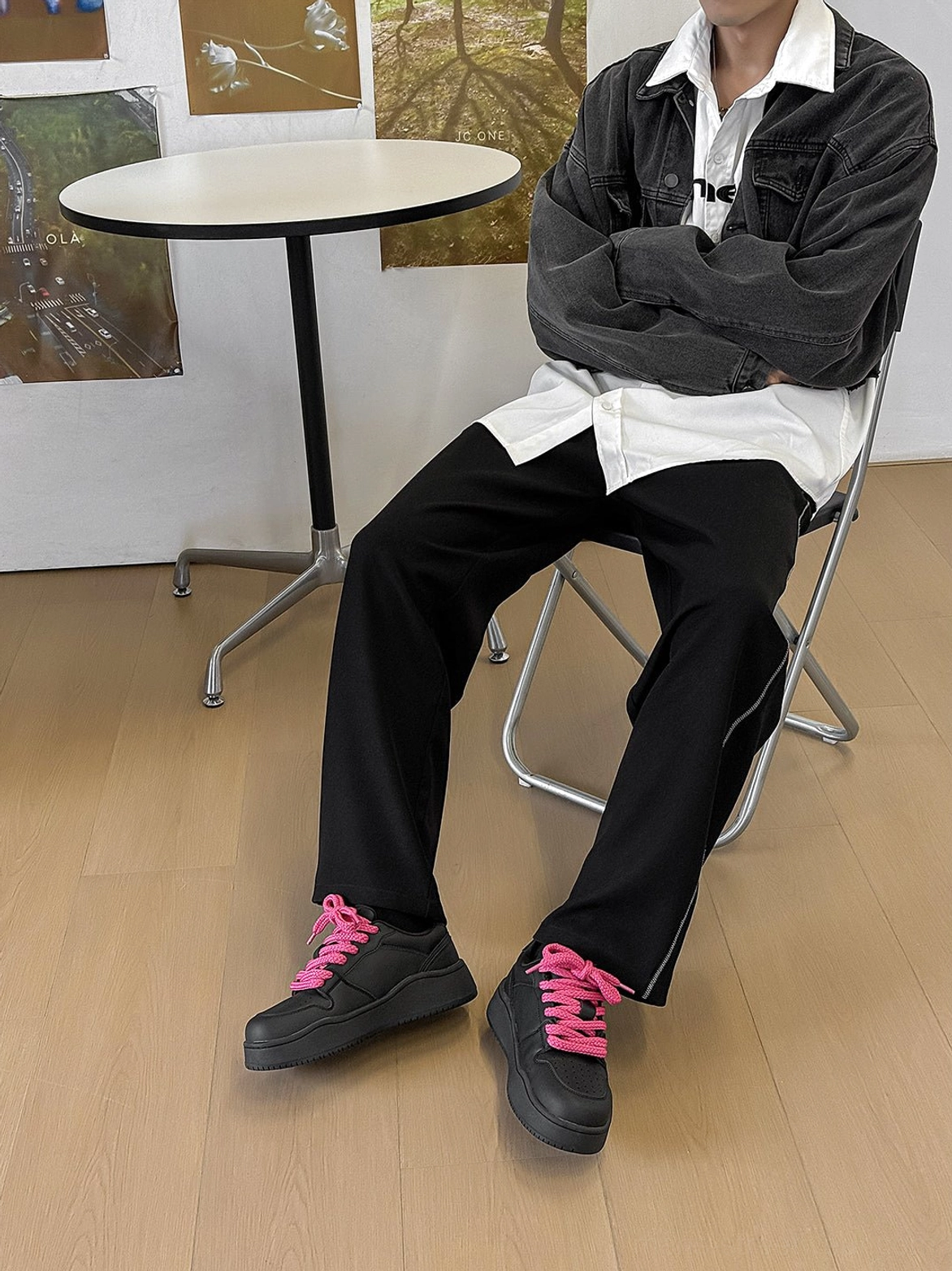Full body streetwear outfit featuring black contrast lace platform sneakers on a seated male model