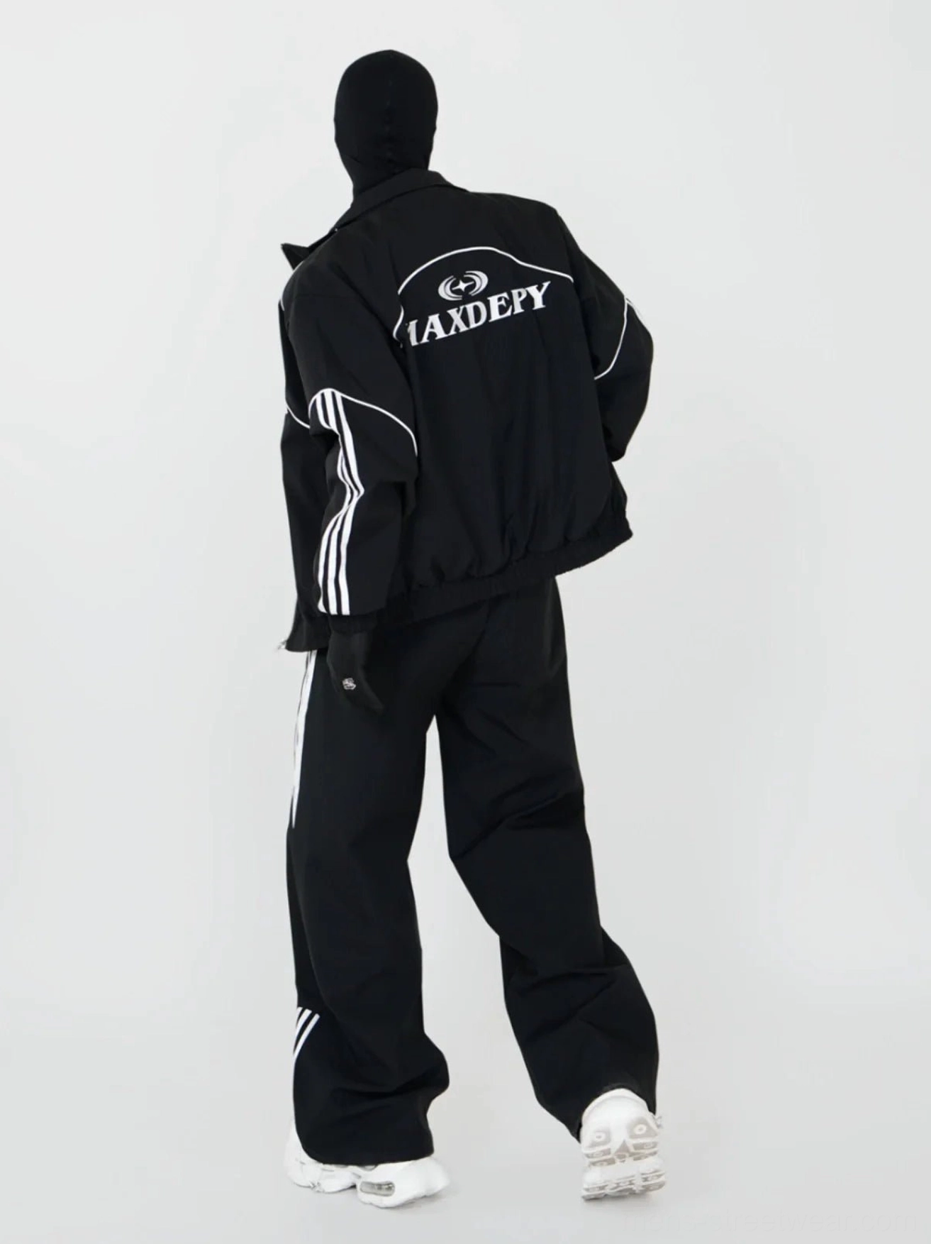 Three-quarter back view of black contrast piping racing jacket and wide-leg track pants streetwear set