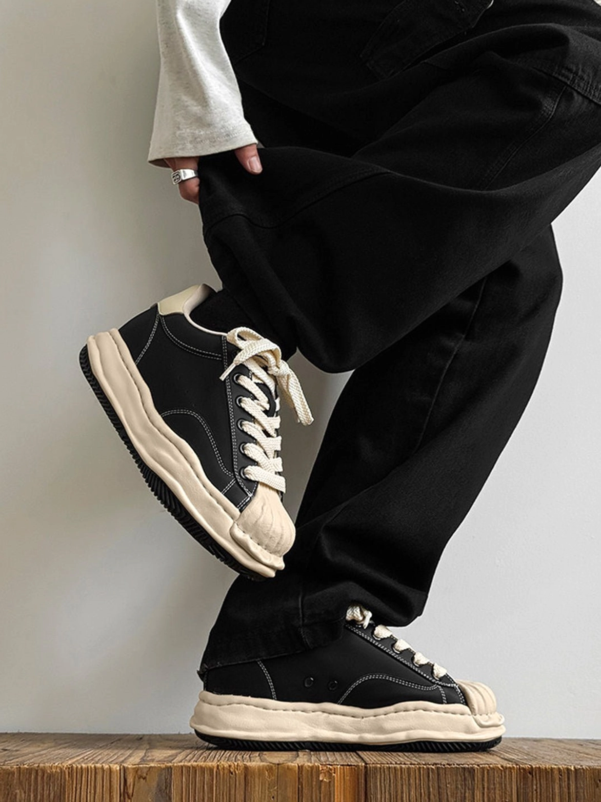 Black and cream platform court sneakers with frayed contrast panels and lace-up streetwear construction