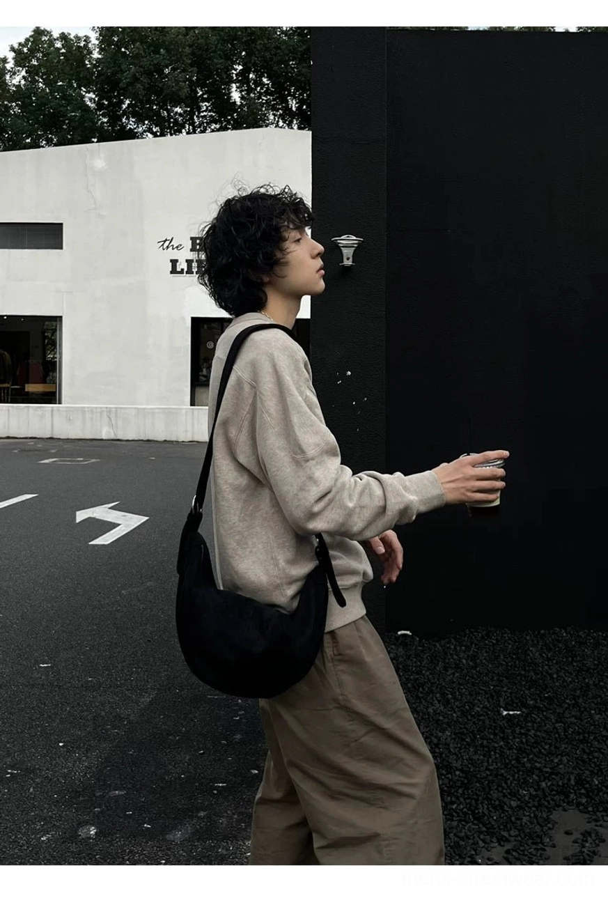 Black crescent crossbody bag full side profile showing compact everyday carry size and wide adjustable strap