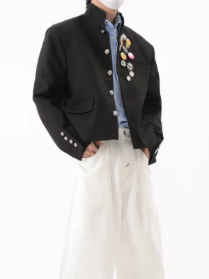 Black crest pin cropped stand collar streetwear blazer shown in left three-quarter front view with silver buttons and decorative chest badges