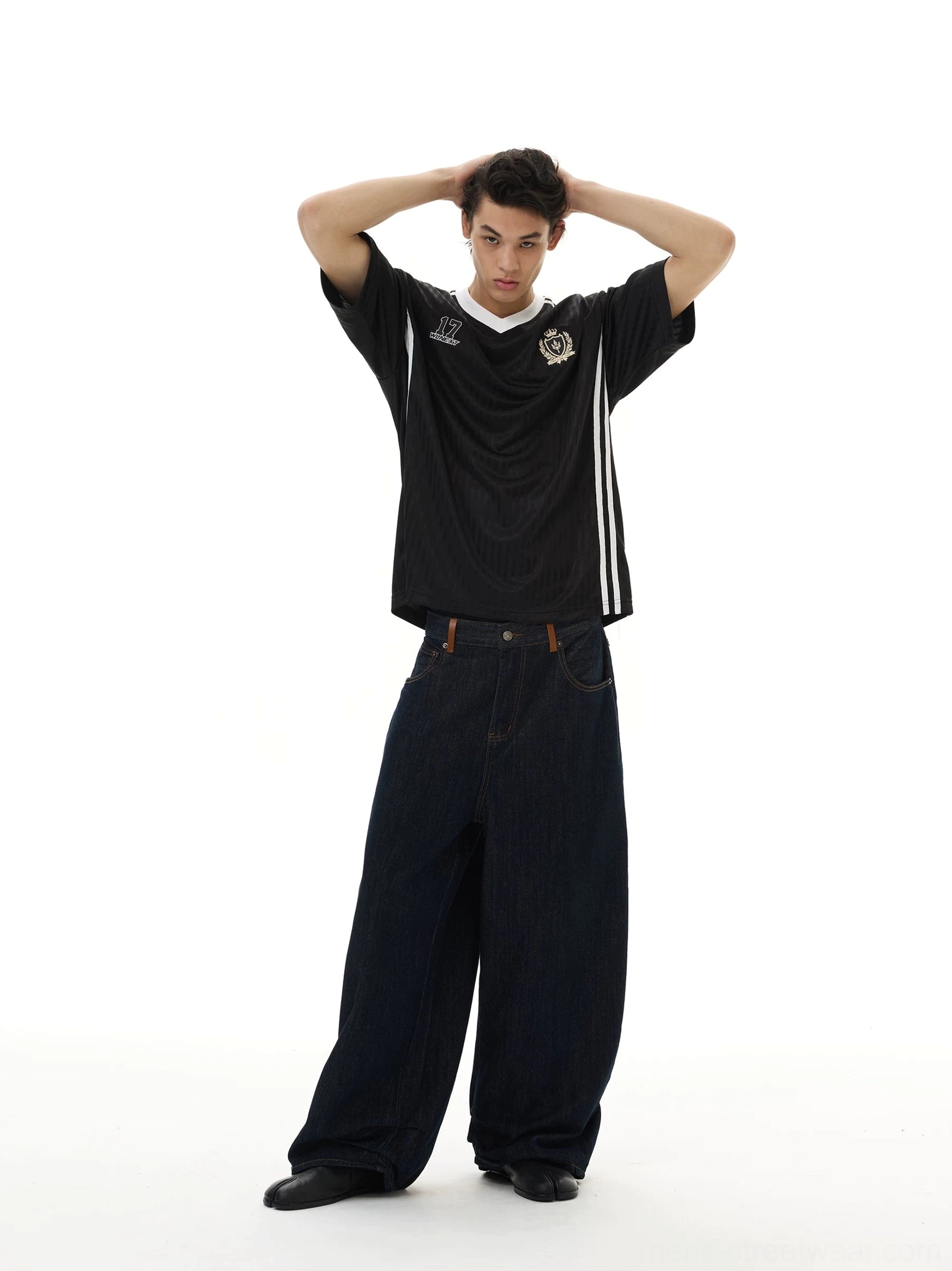 Black crested soccer jersey tee shown in a full front view with V-neck trim, white shoulder stripes, number 17 graphic, and wide-leg denim