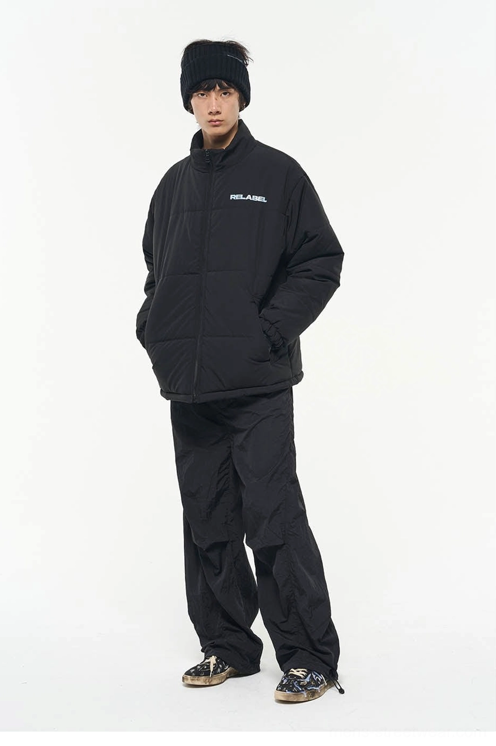 Black nylon wide-leg track pants styled with a matching puffer jacket in a monochrome technical streetwear outfit