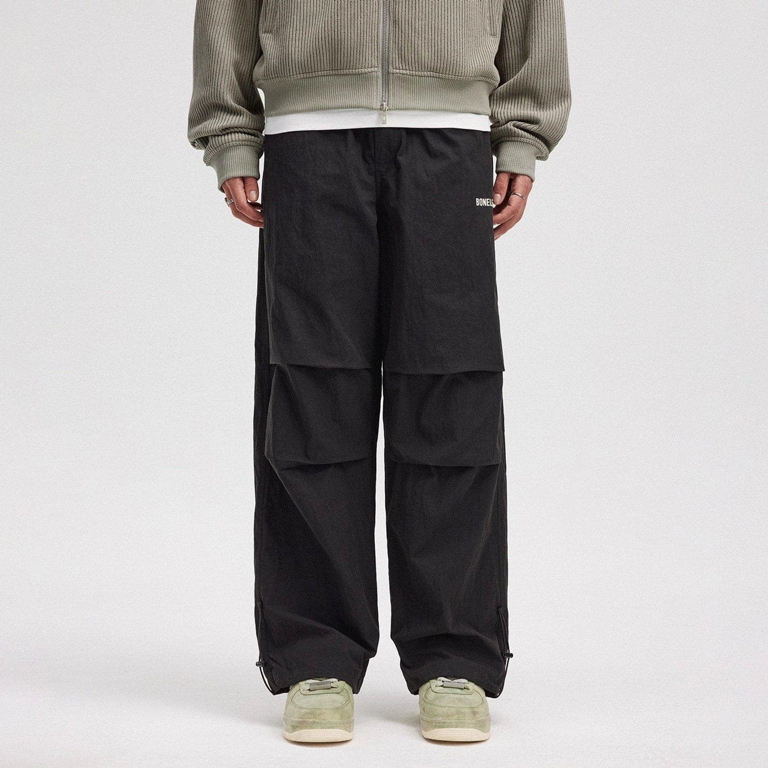 Black crinkled wide-leg drawstring track pants with front pleats styled with neutral sneakers