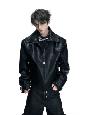 Black crocodile embossed cyber moto jacket worn by male model with silver sunglasses and layered chains in white studio