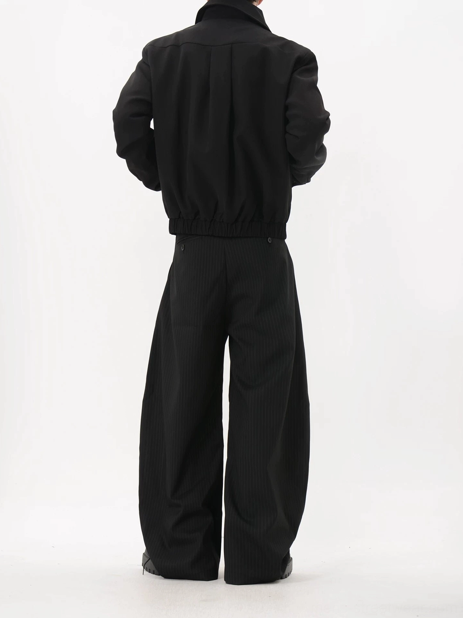Back view of black cropped blouson jacket showing relaxed structured back and gathered elastic hem