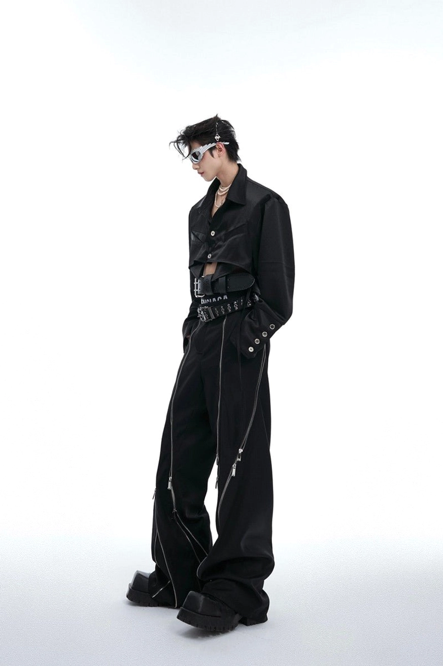Side view of black cropped long-sleeve shirt with exposed underbust hem, decorative cuffs, wide-leg pants, and futuristic streetwear accessories