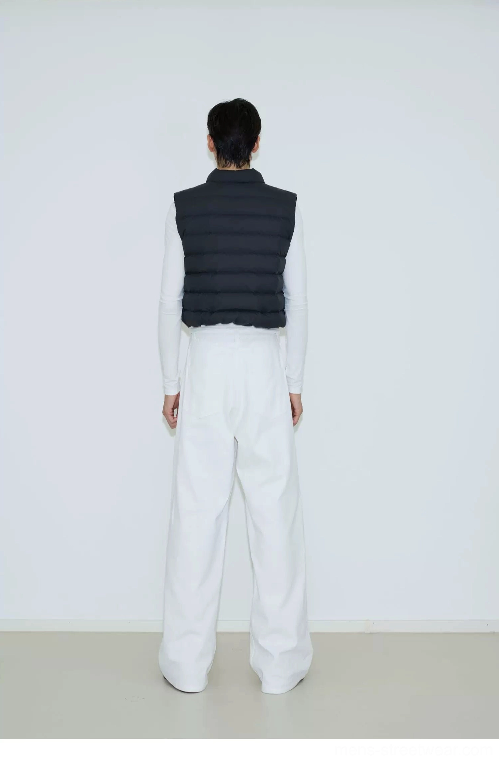 Back view of a black cropped quilted puffer vest showing the neat horizontal padded panel construction