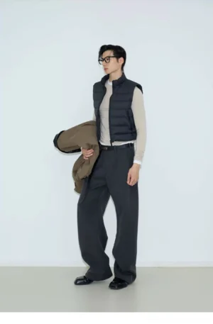 Black cropped quilted puffer vest with stand collar shown from a side view in a minimalist studio streetwear outfit