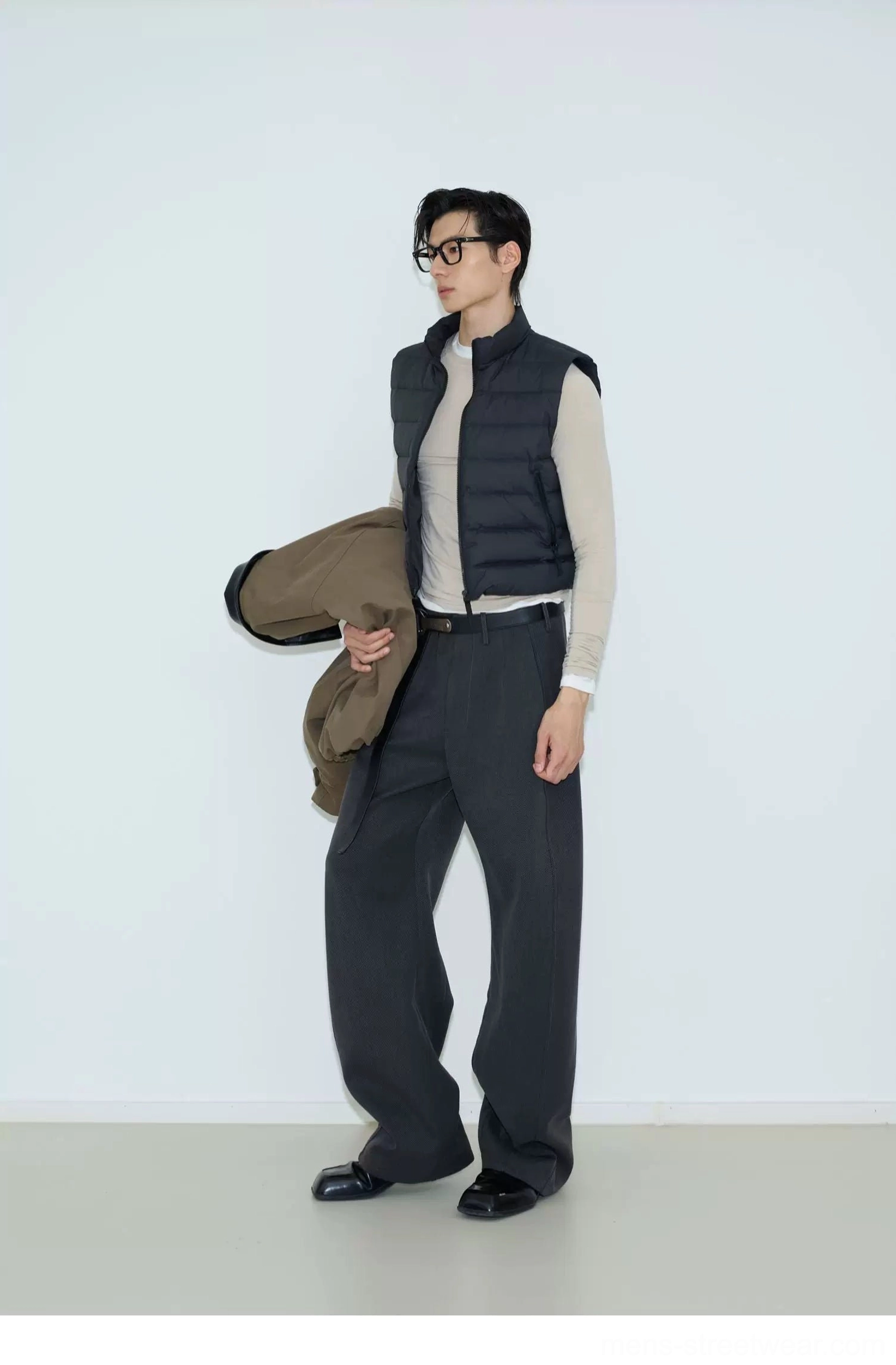 Black cropped quilted puffer vest with stand collar shown from a side view in a minimalist studio streetwear outfit