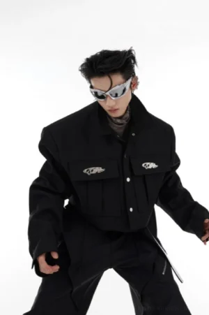 Black cropped shoulder pad cargo jacket worn by male model in white studio front three-quarter view with structured shoulders and flap chest pockets