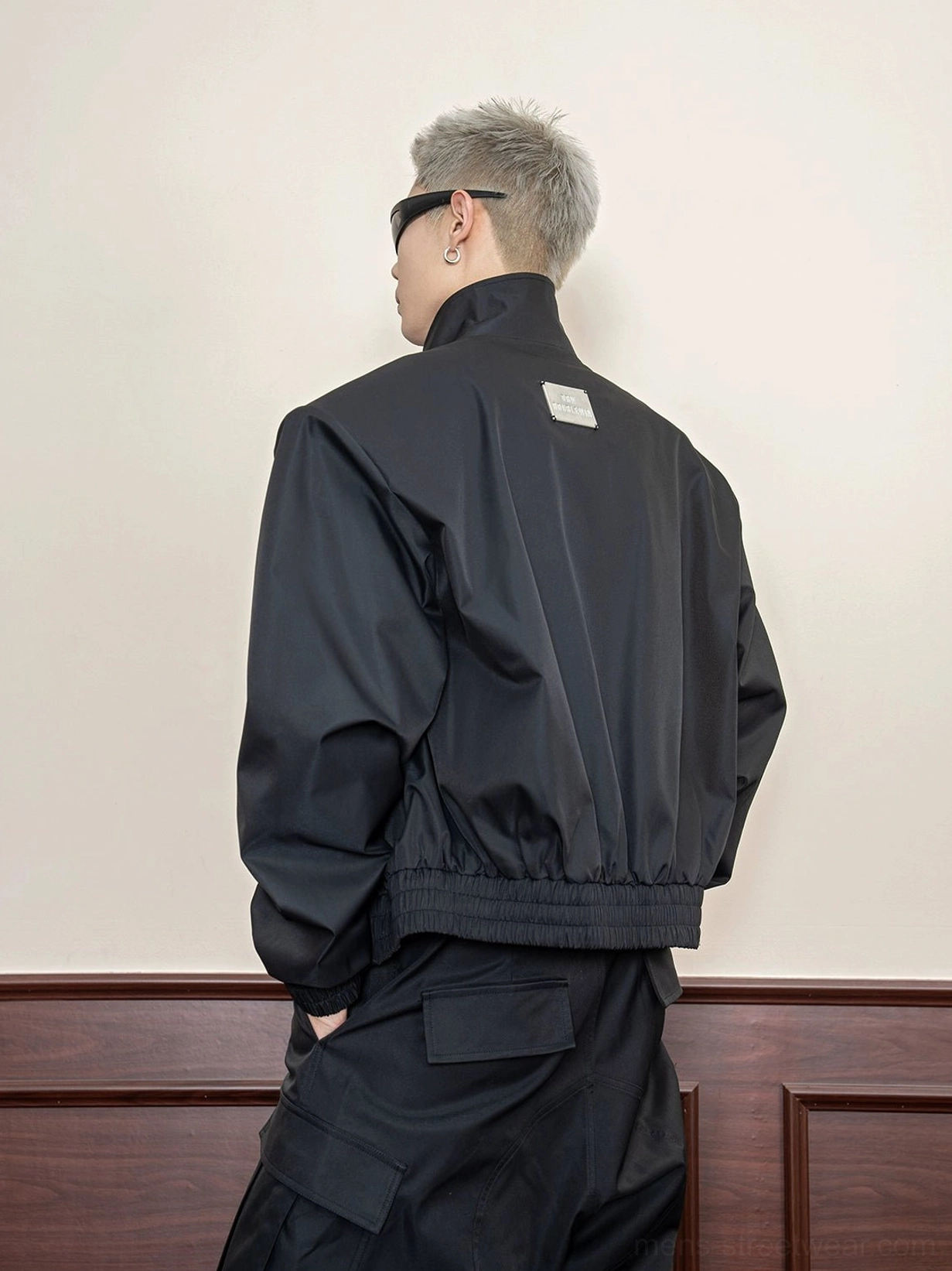 Black cropped techwear utility jacket back three-quarter view showing dropped shoulders ribbed hem and metal back detail