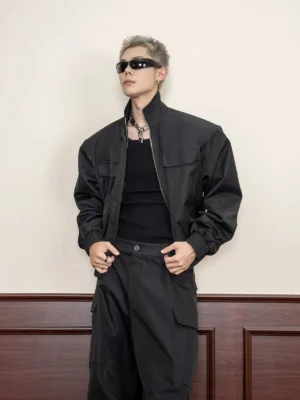 Black cropped techwear utility jacket front three-quarter view with stand collar chest flap pockets and matte fabric