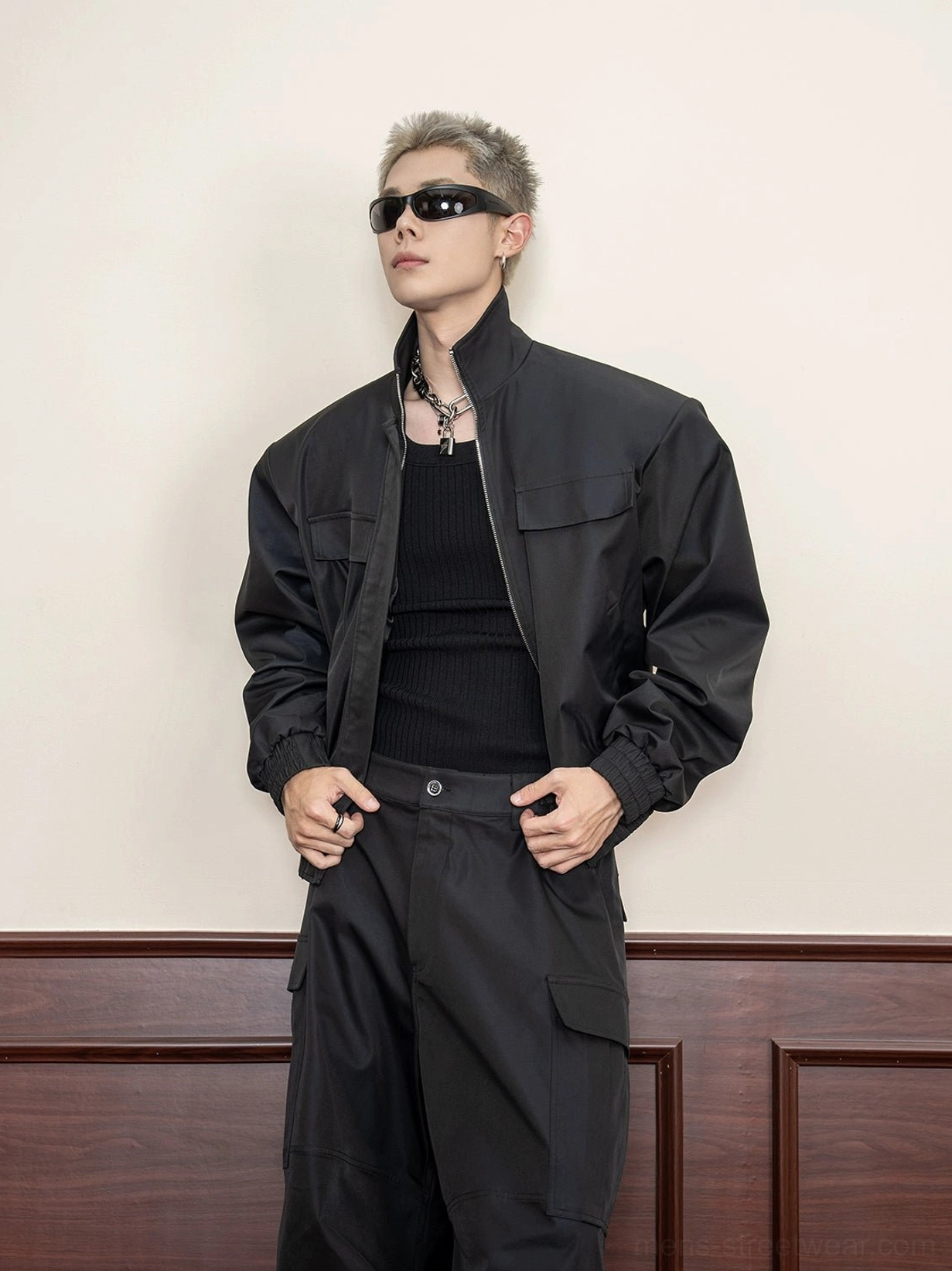 Black cropped techwear utility jacket front three-quarter view with stand collar chest flap pockets and matte fabric