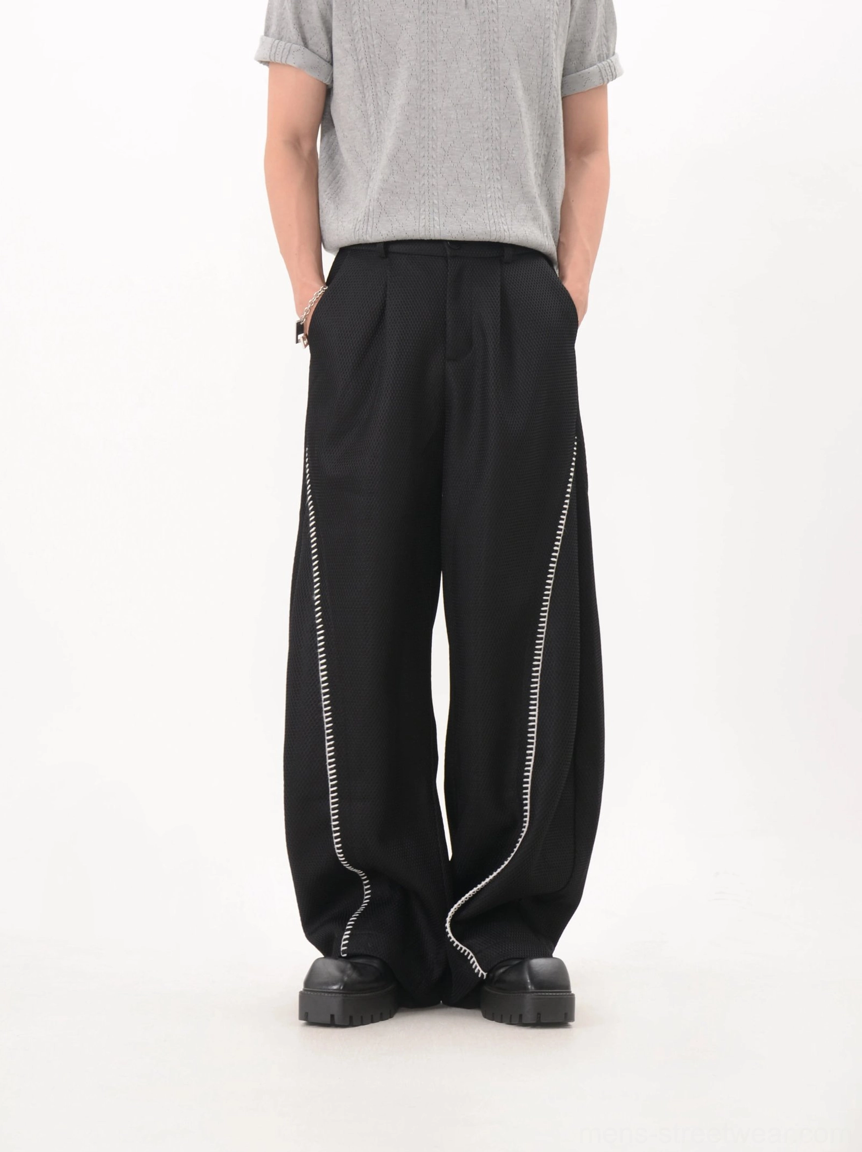 Black curved trim wide leg techwear trousers with pleated waist and long stacked hem front view