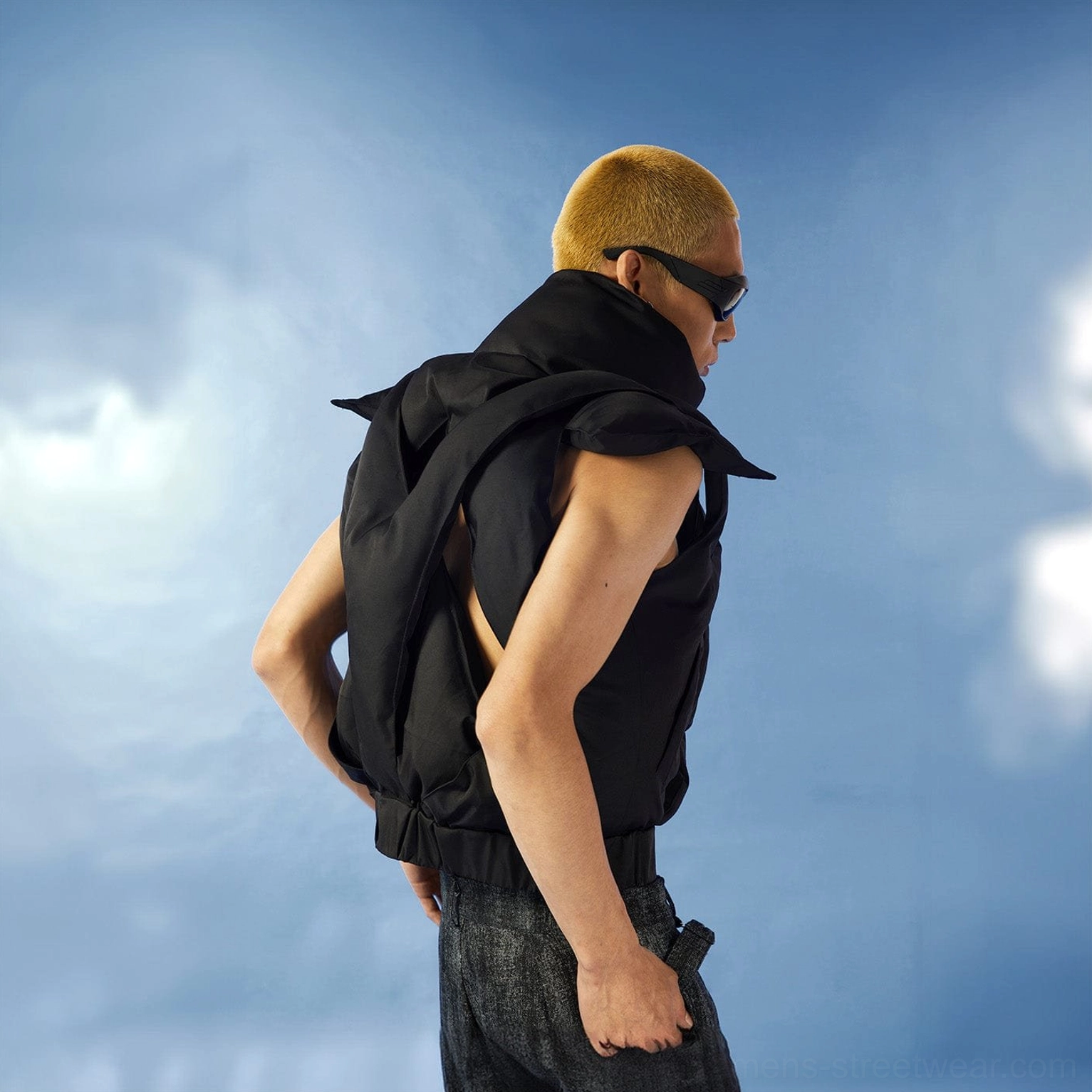 Side profile of black cropped cutout puffer vest with sleeveless structured silhouette high collar and quilted padding