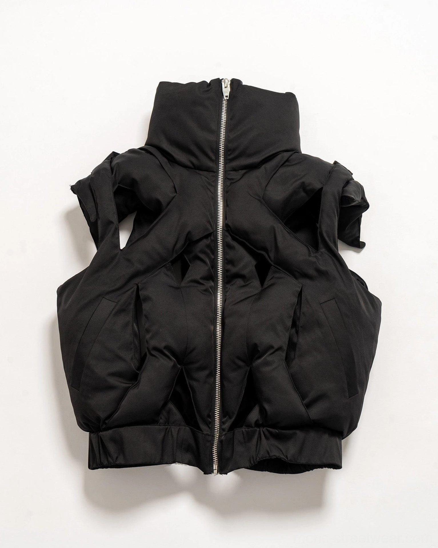Black cropped puffer vest fashion image highlighting its sleeveless design quilted volume and experimental streetwear shape