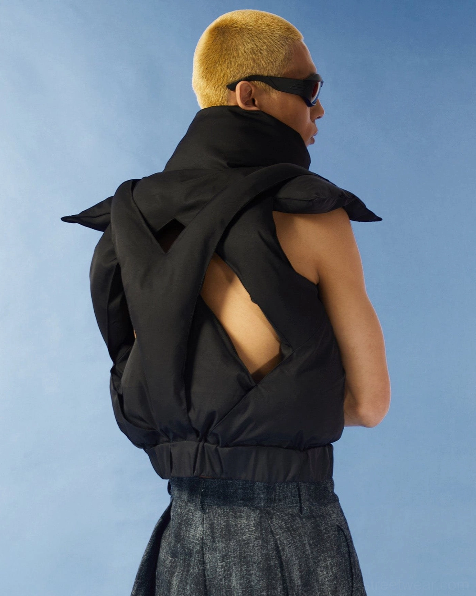 Back side view of black cutout puffer vest with crisscross hollow back quilted panels and cropped Korean streetwear fit