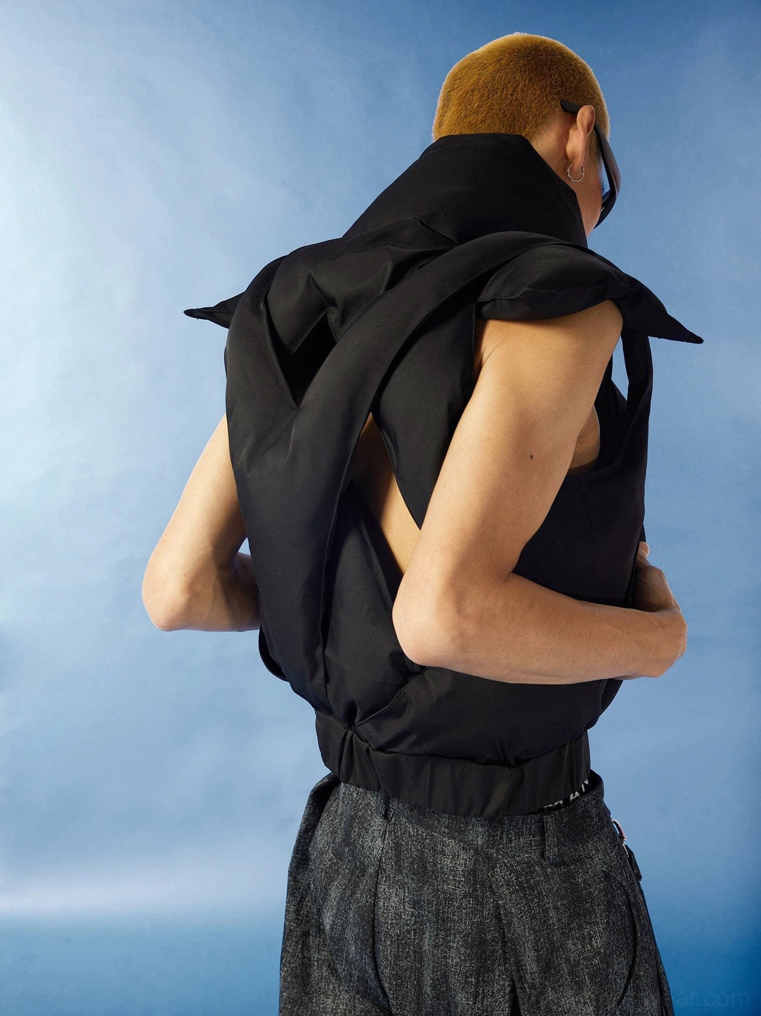 Three-quarter rear view of black sleeveless cutout puffer vest with textured padding cropped hem and Korean streetwear styling