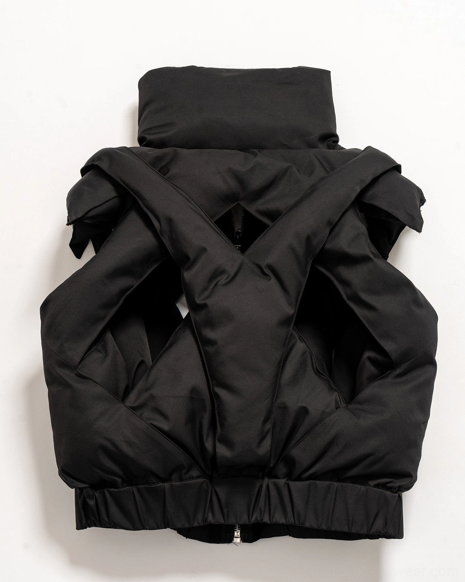 Black techwear puffer vest image with cropped proportions padded texture and statement crisscross cutout styling