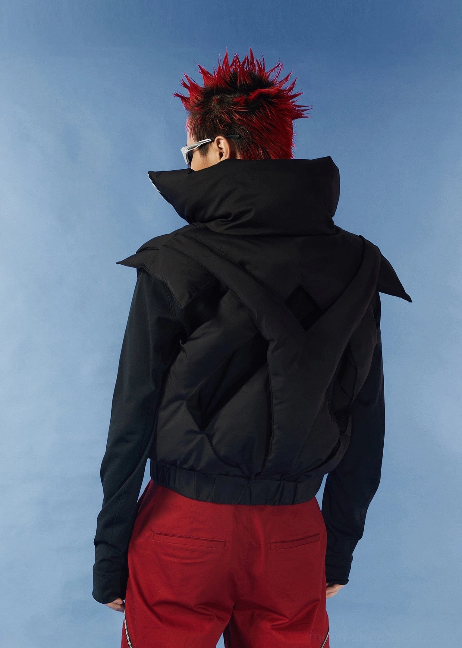 Three-quarter back view of black cropped puffer vest featuring crisscross cutout back high stand collar and layered styling
