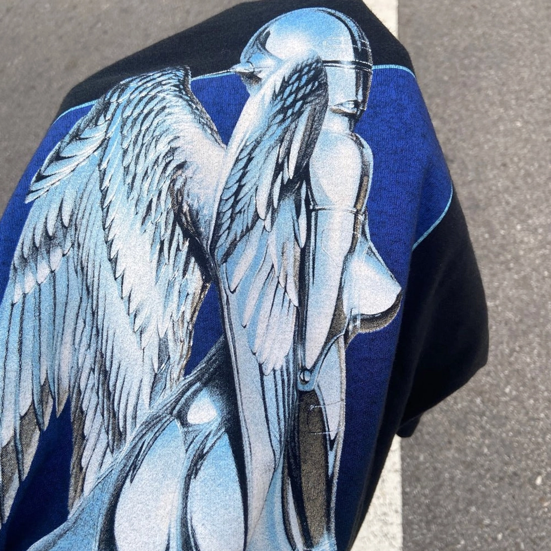 Rear close-up of black cyber angel streetwear t-shirt showing silver winged android graphic on blue square background