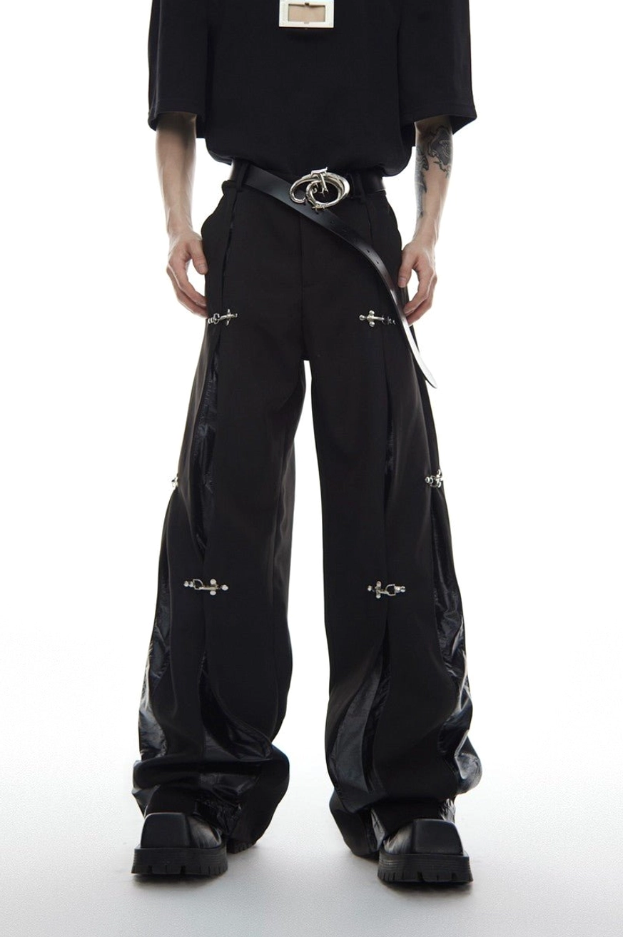 Black deconstructed buckle wide-leg streetwear trousers front view with glossy side panels and silver hardware