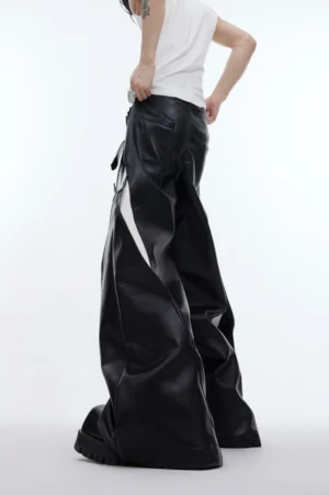 Rear view of black deconstructed faux leather streetwear pants with white side panel, oversized wide-leg cut, and hanging decorative drape