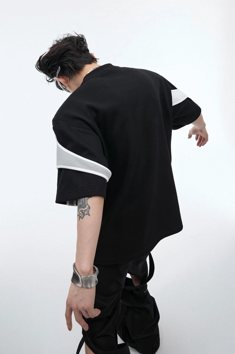 Black deconstructed oversized streetwear t-shirt with white and grey layered shoulder panels shown from a back three quarter view