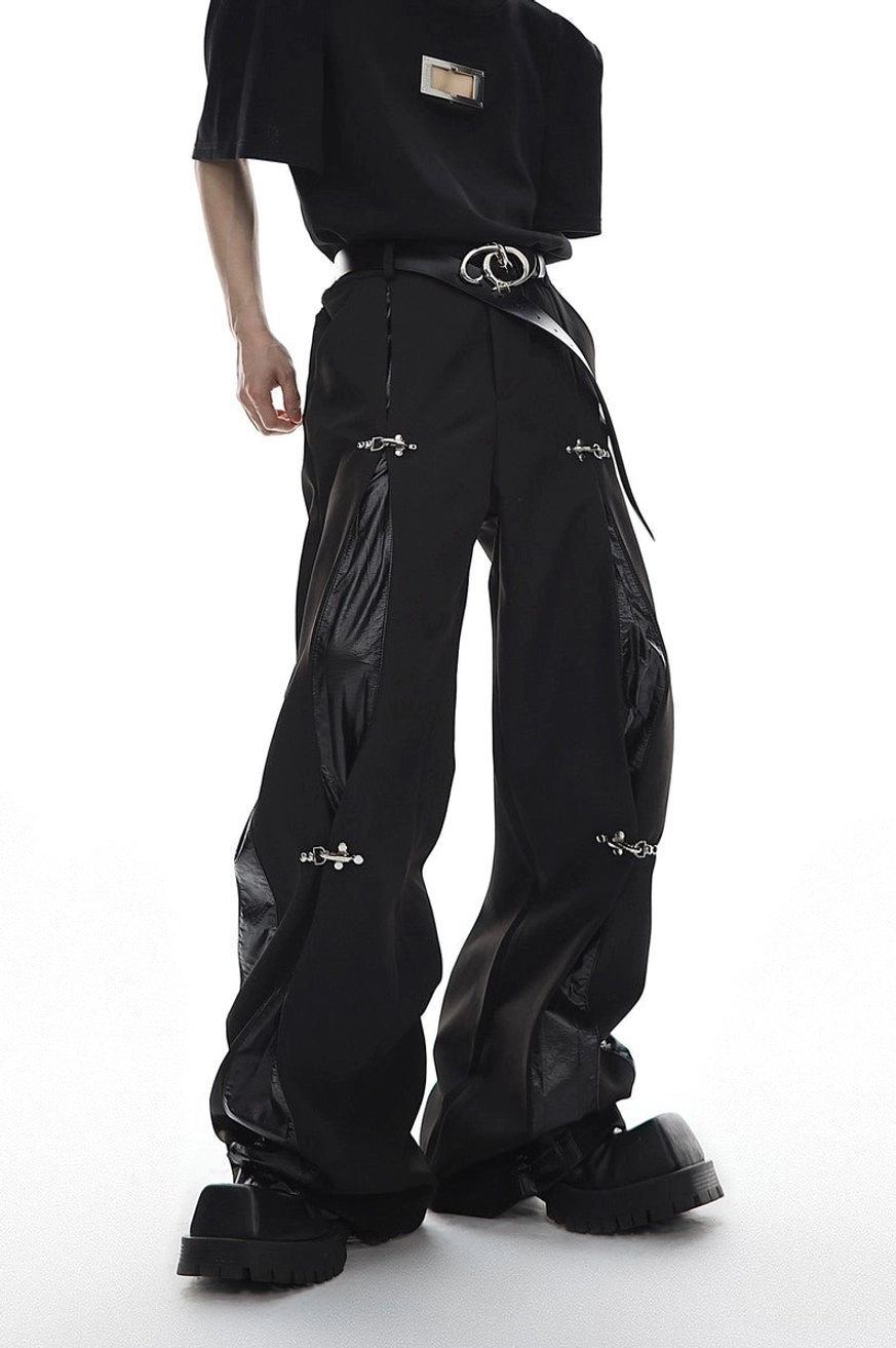Black oversized wide-leg trousers with deconstructed glossy side panels and silver buckle clips three-quarter front view