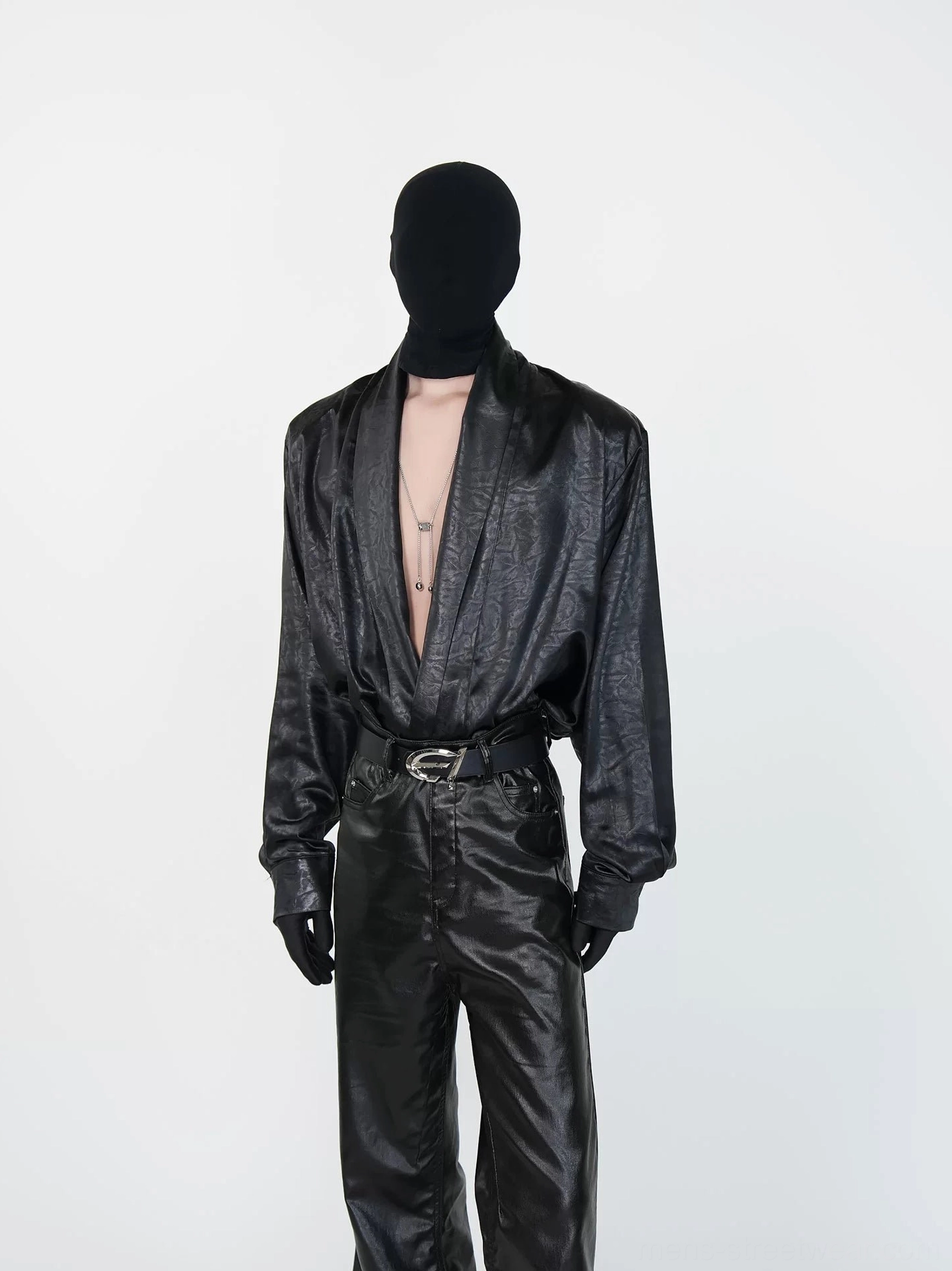 Front view of black deep V faux leather draped shirt tucked into matching flared trousers for avant-garde streetwear styling