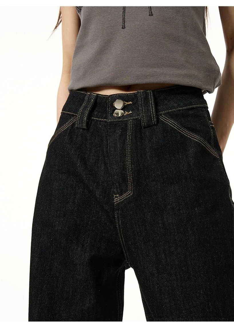 Close-up of the black denim waist and hip area featuring a button fly, belt loops, classic pocket construction, and contrast yellow stitching