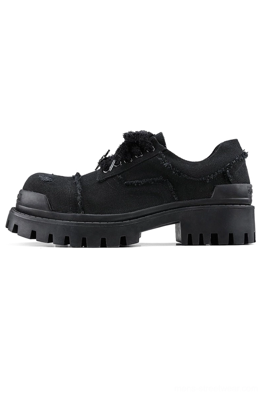 Black distressed canvas platform sneaker in side three-quarter view showing low-top lace-up design and rugged rubber lug outsole