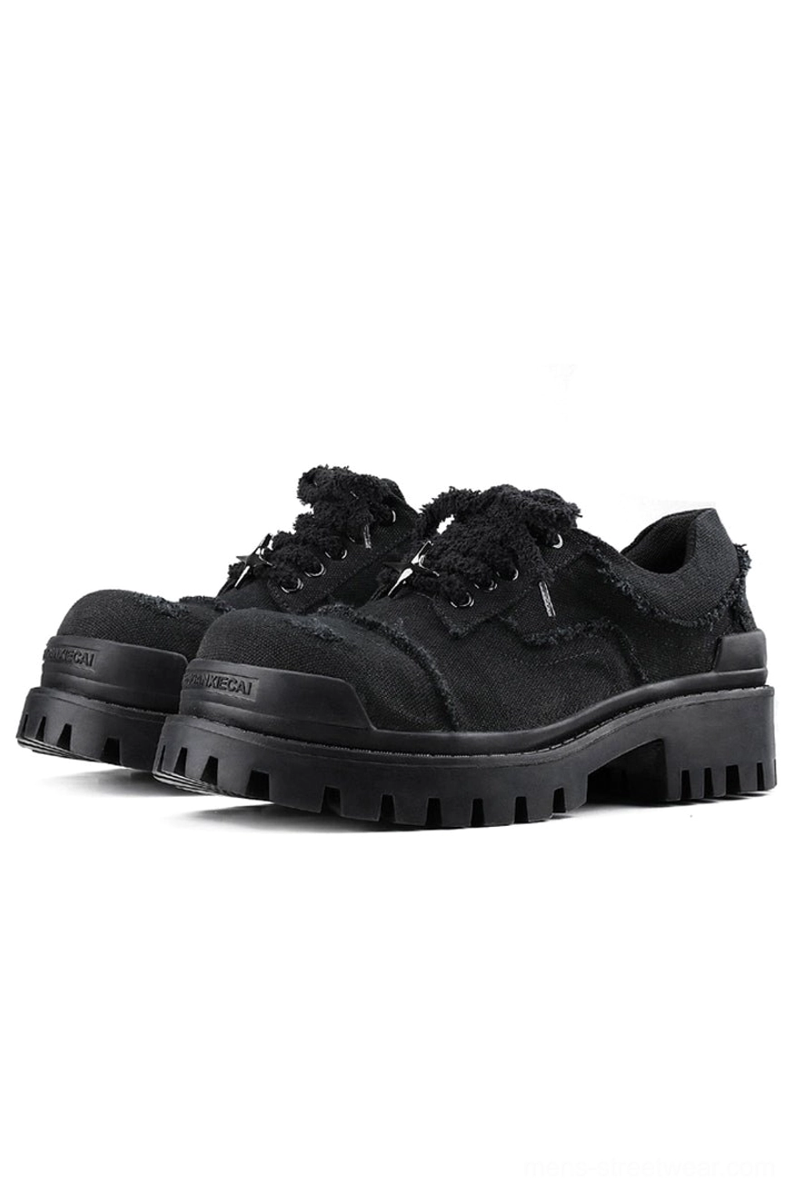 Black distressed canvas platform sneakers pair shown in front three-quarter view with frayed upper and chunky lug sole