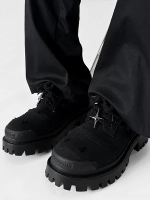 Side on-foot view of black canvas platform sneakers with chunky rubber lug outsole and silver star lace ornament