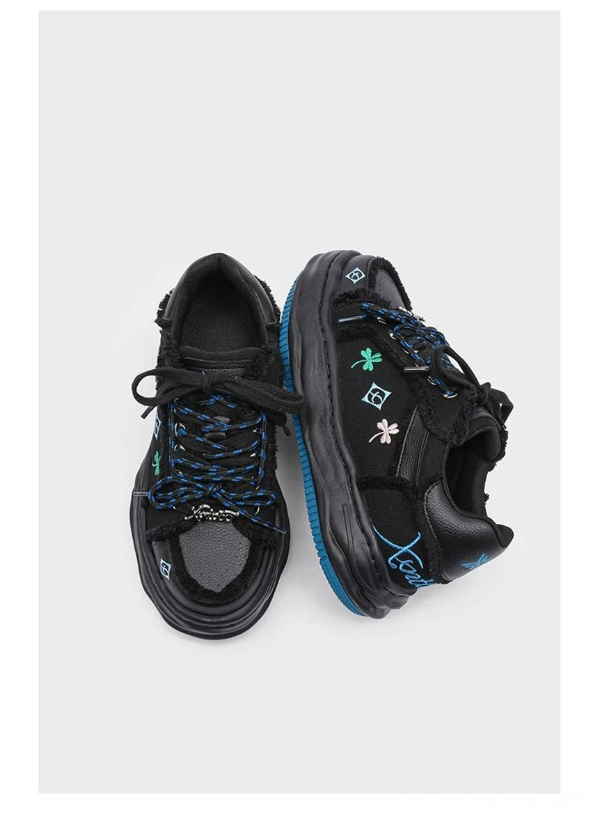 Black distressed embroidered platform sneakers top view with blue clover embroidery frayed upper and blue midsole trim